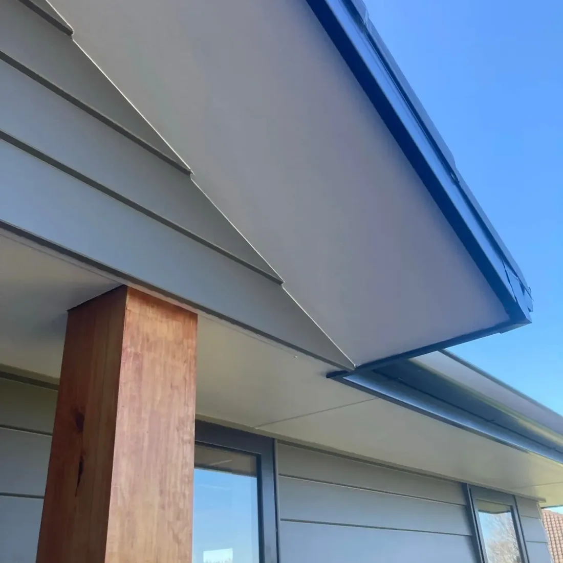 Freshly painted weatherboards and soffit on a new home under a clear blue sky