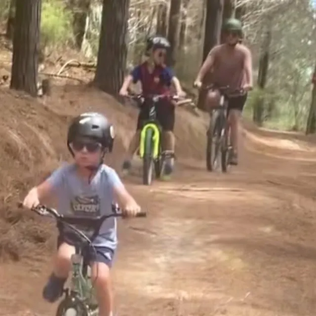 Children and an adult mountain biking on a forest trail
