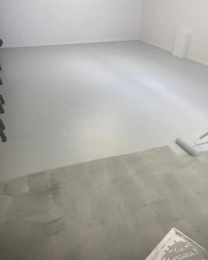 Garage floor part way through being coated in light grey