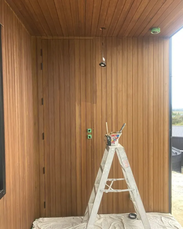 Timber-lined entry walls and ceiling freshly stained, with a painter's ladder in front