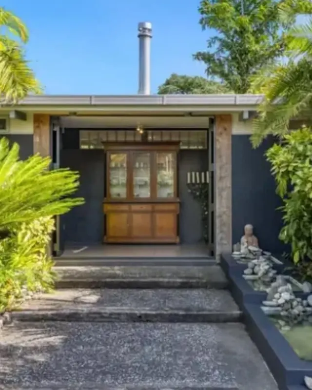 House entrance with dark painted walls, timber posts and palms
